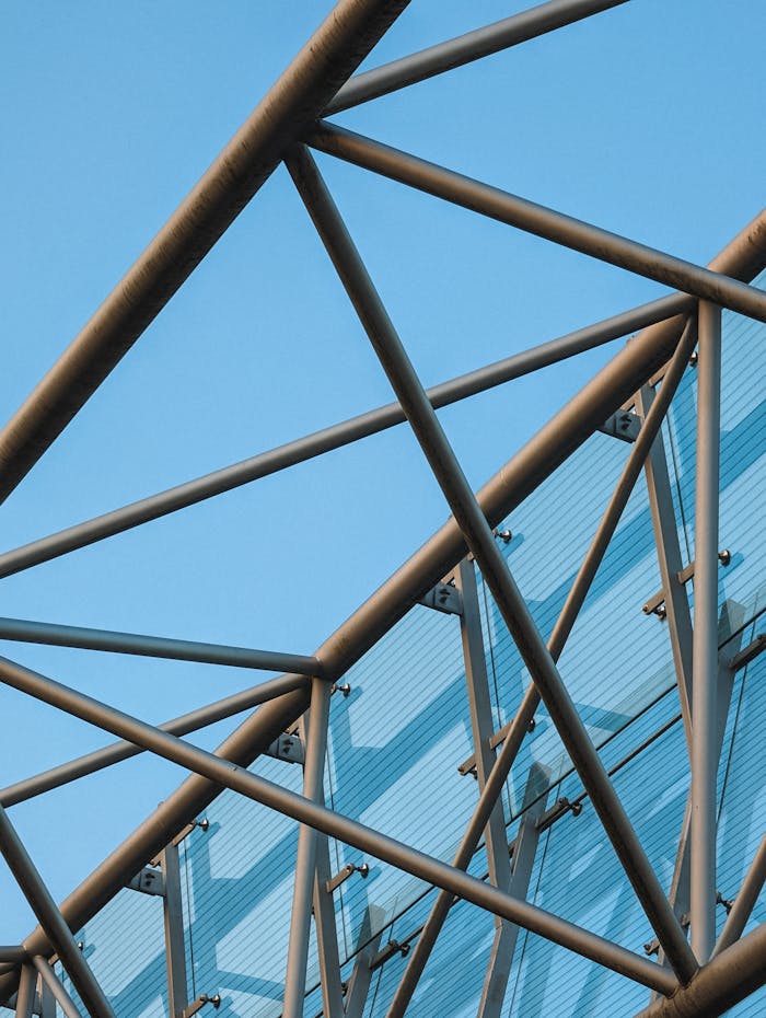 Close-up of a sleek steel framework structure against a clear blue sky.